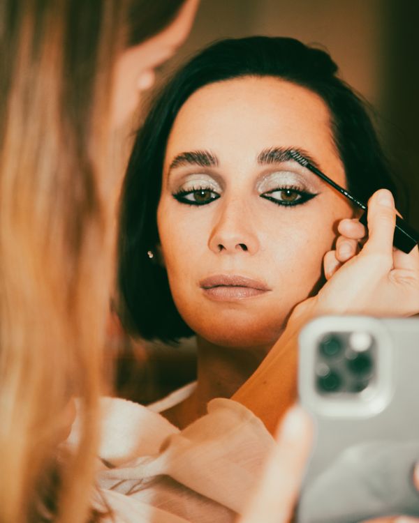 Girl getting her makeup done by a makeup Artist while checking her iPhone