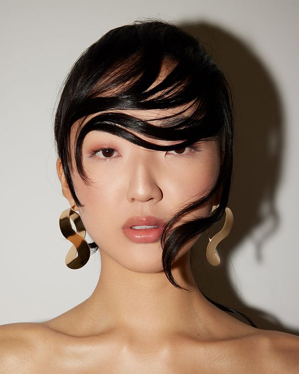 Girl with black hair styled and gelled across her face in a wavy pattern