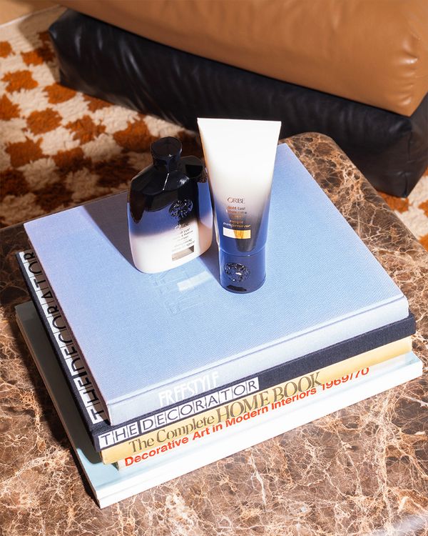 Two Oribe products set on a pile of decorative books 