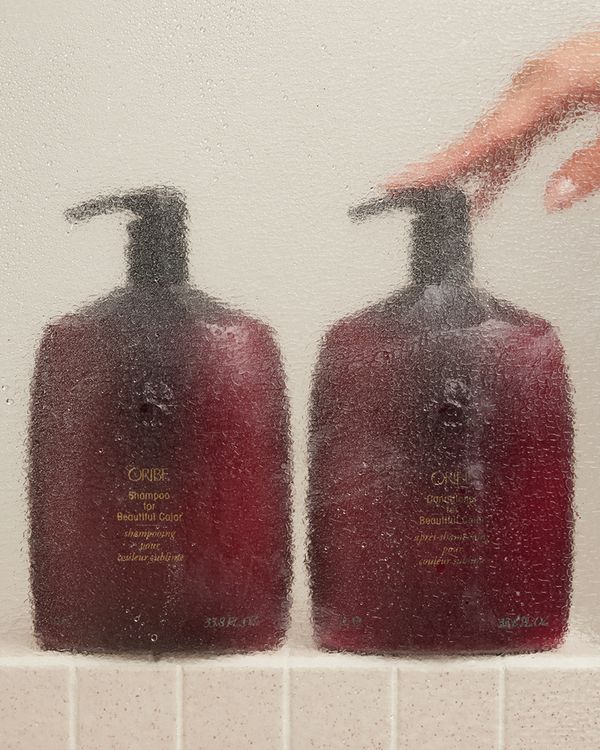 Two red coloured Oribe products behind steamy glass 