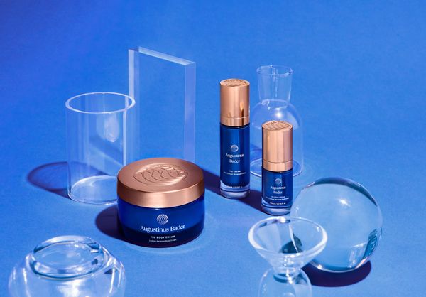 Augustinus Bader's The Body Cream, The Cream and The Rich Cream displaced on a blue backdrop alongside glass decor