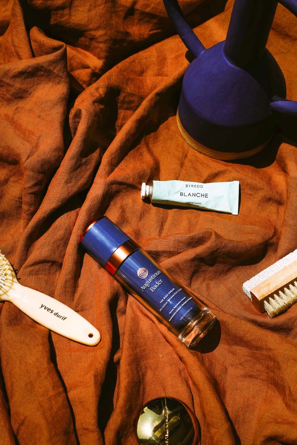 Augustinus Bader's The Rich Cream on an orange towel surrounded by other beauty products and tools
