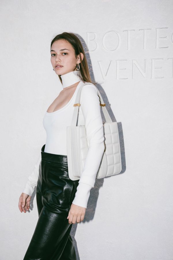 Girl with purse standing in front of Bottega Venetta backdrop 