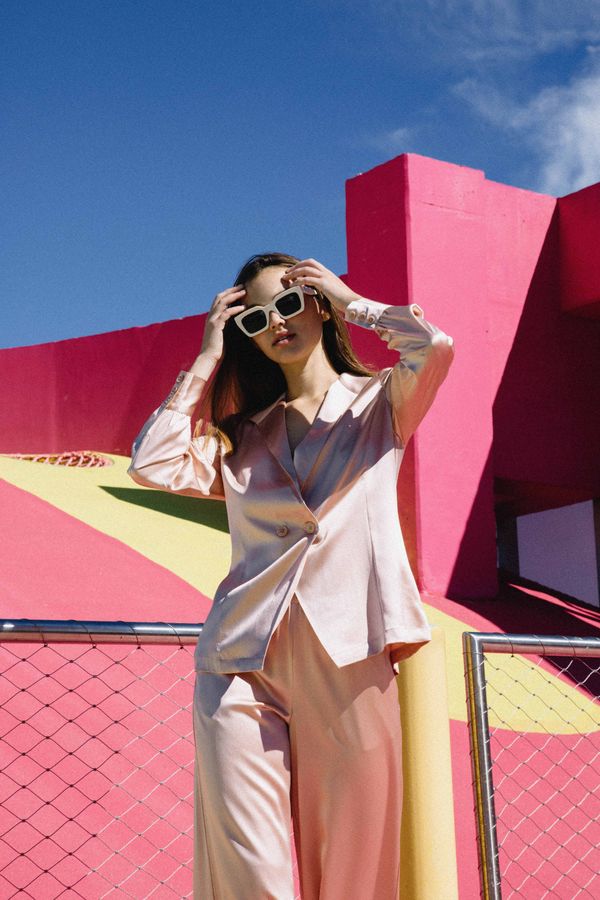 Girl in silk outfit posing in front of pink structure
